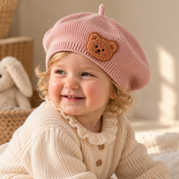 Béret bébé en maille rose avec écusson ourson porté trois quart