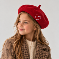 Béret fille rouge avec cœur blanc brodé porté sur le coté 